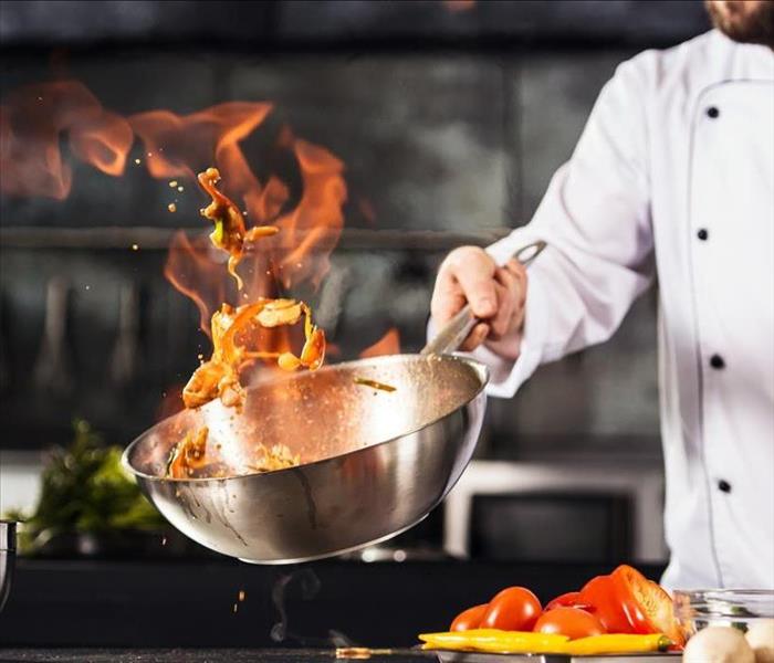 Chef hands keep wok with fire. Closeup chef hands cook food with fire.